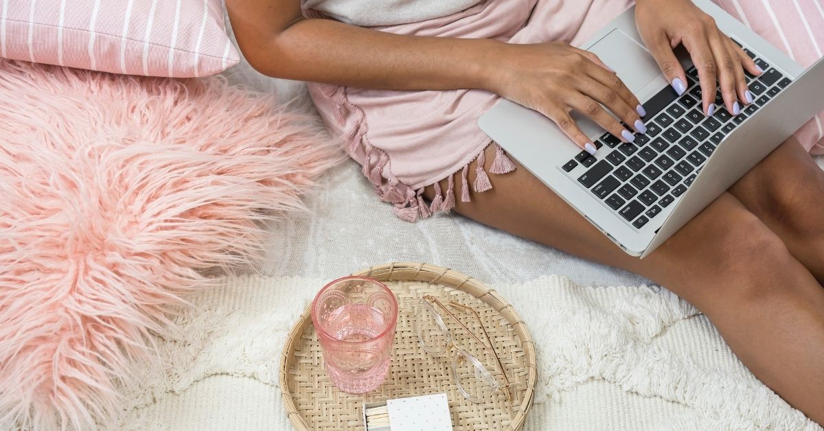 a woman working on her bed on her blog post